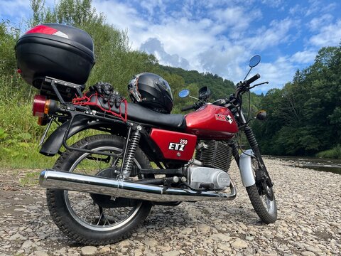 Vintage Motorcycle MZ ETZ 250 parked on a Gravel Road in Forest Landscape