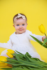 little girl in white dress on yellow background. Cheerful happy child with tulips flower bouquet