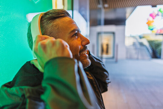 Smiling man listening to music with headphones in urban business district