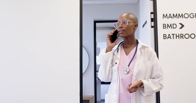 African woman clinician receiving scheduling call in clinic doorway holding phone checking watch