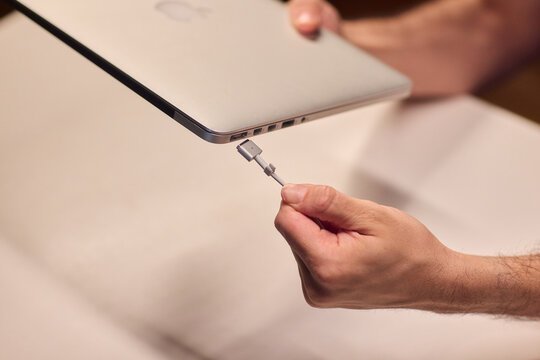 Hand repair issue, Closeup of hands fixing loose laptop connector in city environment, Detailed shot of malfunctioning laptop cable with frayed insulation during commute