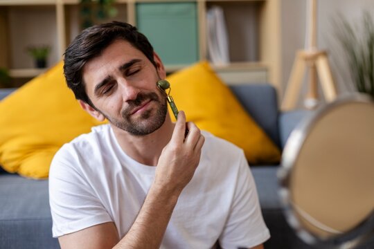 Man using jade roller for facial massage and self-care at home