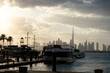 Obraz premium Dubai skyline at golden hour with dramatic sunset sky and calm water waves, Dubai Creek Harbor view 4k cinematic background