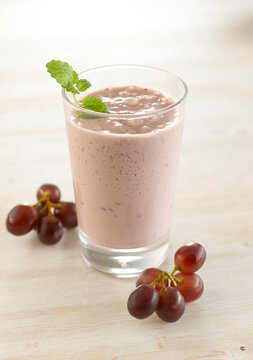 Grape smoothie in glass with mint and fresh grapes on table