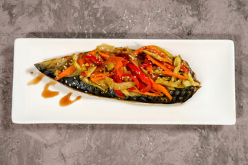Fried mackerel fish with vegetables served on a white plate ready to be served in the dining room.