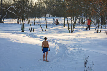 Hardening in winter, man with a naked torso standing in snowy park in frosty weather. Strengthening of immunity