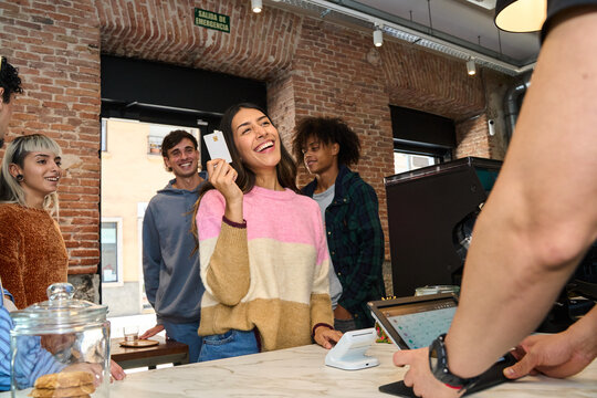 Friends enjoying socializing at a modern shop paying with contactless card