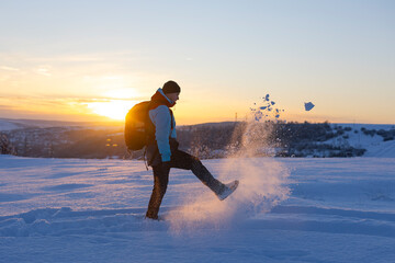 Man having fun in snow covered mountain in magic sunset. Active people in nature, adventure concept