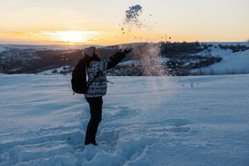 Woman having fun in snow covered mountain in magic sunset. Active people in nature, adventure concept