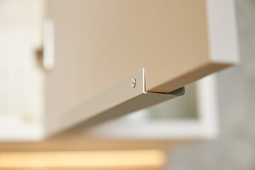Close-up of contemporary white kitchen cabinets with integrated handle and lighting.