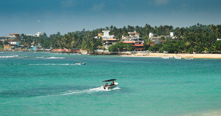 Obraz premium Dynamic Coastal View with Boats and Lush Greenery Nearby