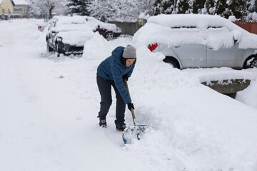 Woman removes snow on the street on a winter morning.