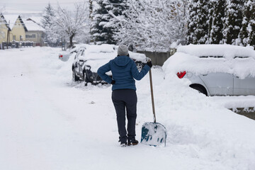 Woman removes snow on the street on a winter morning.