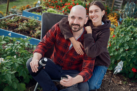 Couple relaxing with coffee in wheelbarrow at London allotment garden