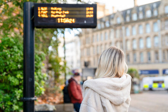 Waiting for the bus in the city with the schedule board showing arrival times