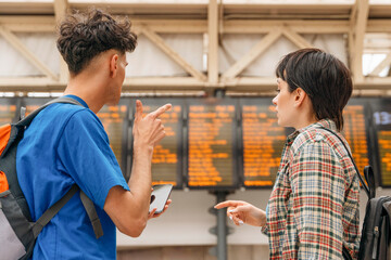 People look at train schedule board at station in daytime
