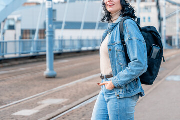 Young woman stands on the bridge with a backpack and smiles  