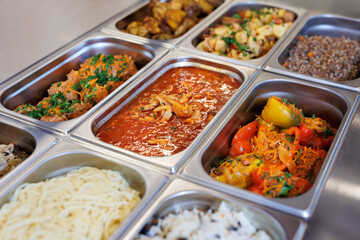 Freshly cooked delicious food in buffet serving trays at a self-service restaurant.
