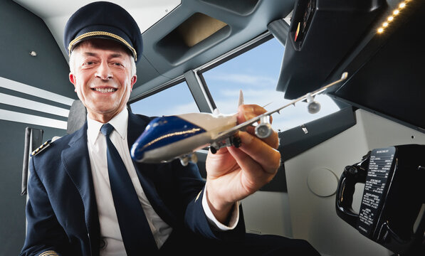 Pilot in cockpit holding airplane model smiling at Bavaria Studio Munich