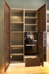 Modern built-in wardrobe with open doors, shelves and appliances.