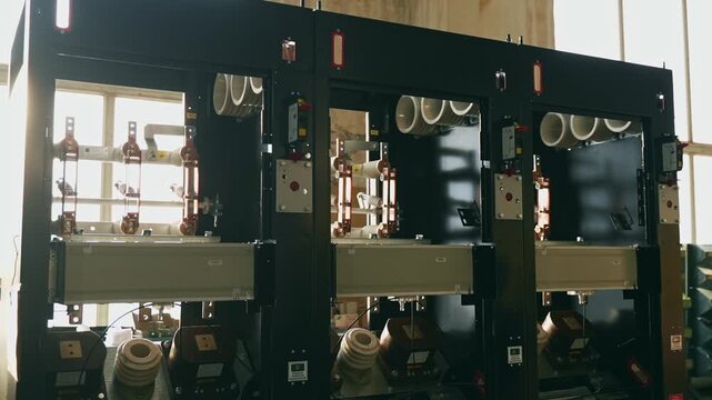 Industrial high voltage electrical switchgear cabinets with ceramic insulators and copper busbars inside factory. Power distribution, energy infrastructure and industrial technology concept.