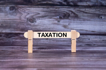 Fototapeta premium Taxation symbol. A wooden stick secured by Clothespins set over beautiful Realistic Wooden Texture Background. Business and Taxation concept with copy space