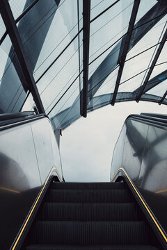 Modern interior escalator with glass reflection and symmetry lines in architecture guiding transport ascent for business travel and momentum