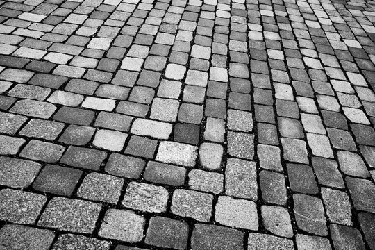Close up cobblestone pavement stone texture pattern on urban street background in monochrome with rough surface for abstract design use