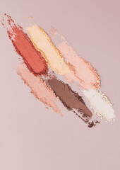 A beautiful parallel eye shadow strokes in brown shades on a beige background. top vertical view. A copy space. texture sample decorative cosmetics