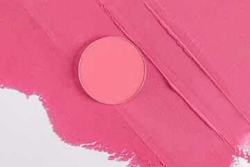Round block, a refill of pink blush lies on a background of dry blush with pattern. the texture of the cosmetic product. layout for design. top view
