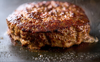 grilling hamburger beef patty on grill, selective focus.
Barbecue traditional hamburger beef patty.