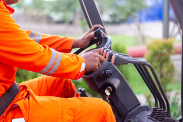 Skilled Operator in Bright Orange Protective Uniform Manipulating Forklift Controls During Material Handling © agung