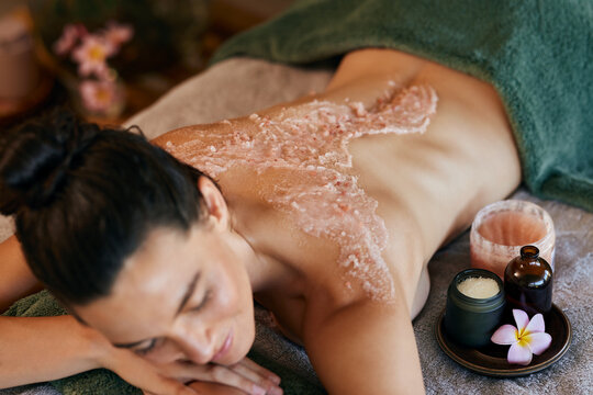 Woman enjoying body scrub on back at luxury spa