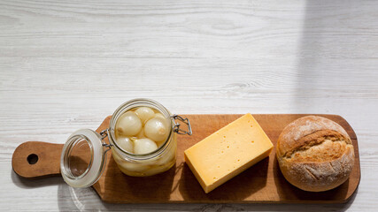 Tasty snacks on a wooden board with cheese, bread, and pickled onions ready for enjoyment