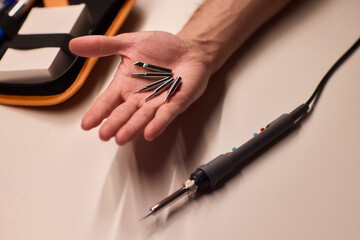 Detailed view of soldering iron and electronic components setup, Scene depicting meticulous preparation for circuit fixing and part assembly involving soldering tools
