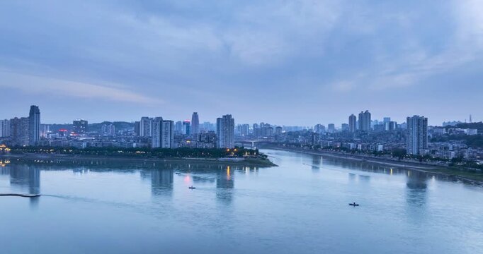 Aerial time-lapse of Luzhou cityscape at twilight, the confluence of Yangtze and Tuojiang rivers with illuminated city skyline and calm water reflections, China