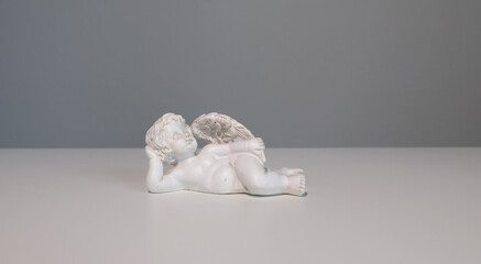 White ceramic angel figurine on white background for design. Faith, symbols, and traditions.