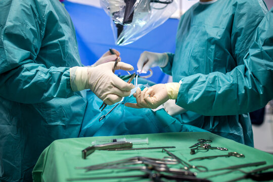 Professional surgical team performing an operation in a modern hospital with specialized stainless steel medical instruments on a green sterile table during a complex clinical procedure - Powered by Adobe