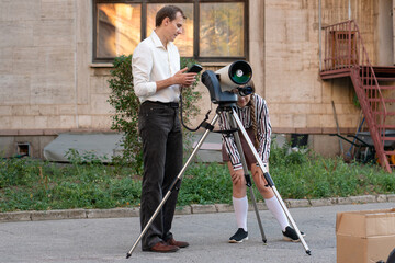 Student bends to observe through a telescope while the teacher supervises nearby, during an outdoor astronomy session focused on science learning and discovery