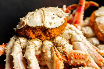 Freshly cooked king crab displays bright orange roe beneath its shell, with claws and legs surrounding the body, illustrating marine life and seafood harvesting detail