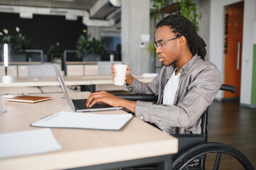 Focused african american employee with disability working on laptop in modern office