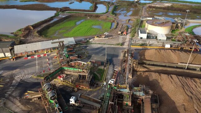 Top down drone footage showing industrial sugar processing tanks and complex pipework systems with brown water in Newark United Kingdom