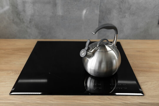 Photo of gray stainless steel kettle on the induction cooktop in the kitchen.