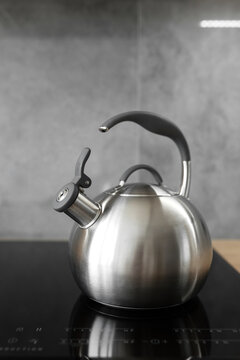 Photo of gray stainless steel kettle on the induction cooktop in the kitchen.