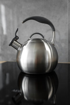Photo of gray stainless steel kettle on the induction cooktop in the kitchen.