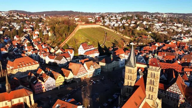 Aerial cityscape reveals Esslingen's medieval city center dominated by Frauenkirche twin church towers above red-tiled architecture, Swabian Gothic style, Marktplatz square visible, Stuttgart