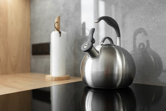 Photo of gray stainless steel kettle on the induction cooktop in the kitchen.