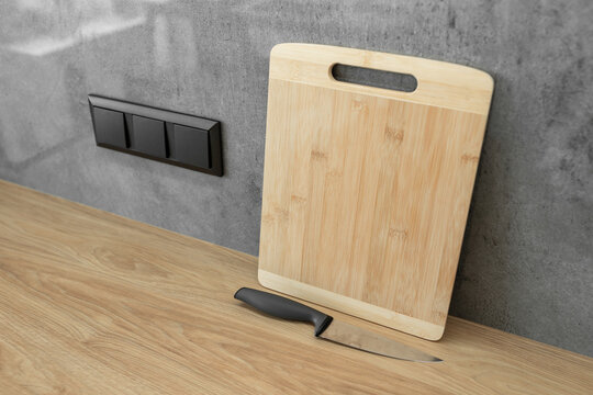 Sharp stainless steel kitchen knife resting near a wooden cutting board.