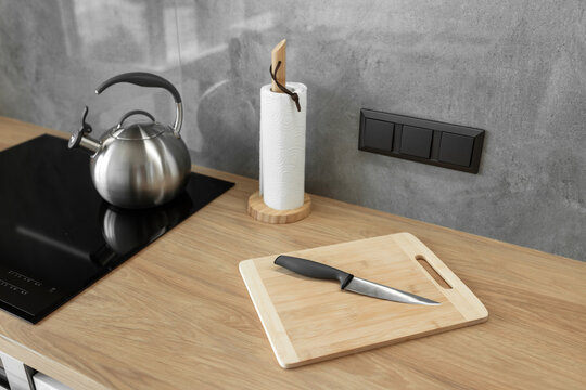 Photo of gray stainless steel kettle on the induction cooktop in the kitchen.