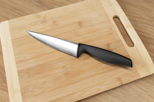 Sharp stainless steel kitchen knife resting on a wooden cutting board.